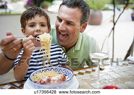 Father and son eating spaghetti View Large Photo Image Stock Photo - Father and son eating spaghetti. Fotosearch