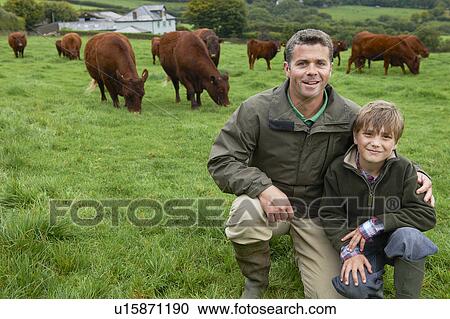 Stock Image - Father and son on farm with cows. Fotosearch