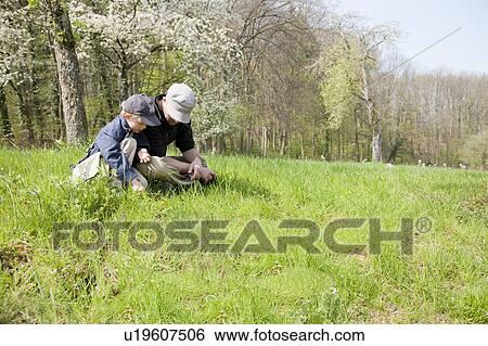 Stock Photograph - Father and son sitting in a field. Fotosearch