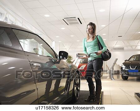 Stock Photograph - Female customer looks at car. Fotosearch