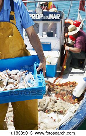 Stock Image - Fisherman holding tray of fresh fish. Fotosearch
