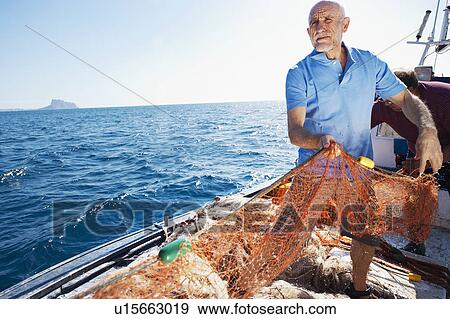 Fisherman on boat pulling in nets View Large Photo Image Stock Photo - Fisherman on boat pulling in nets. Fotosearch