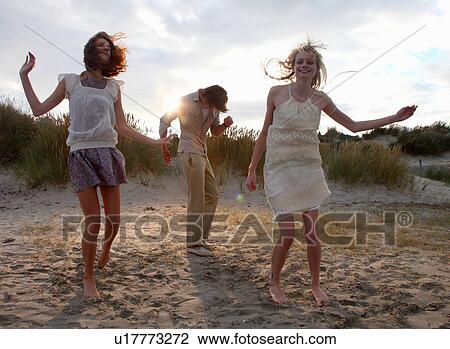 Friends dancing at the beach at sunset View Large Photo Image Stock Image - Friends dancing at the beach at sunset. Fotosearch