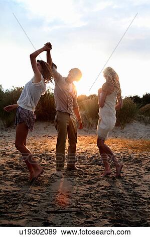 Stock Photo - Friends dancing at the beach at sunset. Fotosearch