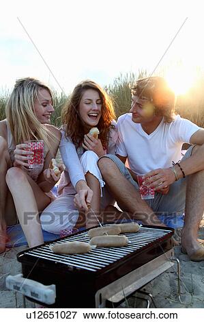 Friends having a beach BBQ at sunset View Large Photo Image Stock Photo - Friends having a beach BBQ at sunset. Fotosearch