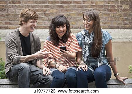 Friends sharing joke on mobile outside View Large Photo Image Stock Image - Friends sharing joke on mobile outside. Fotosearch