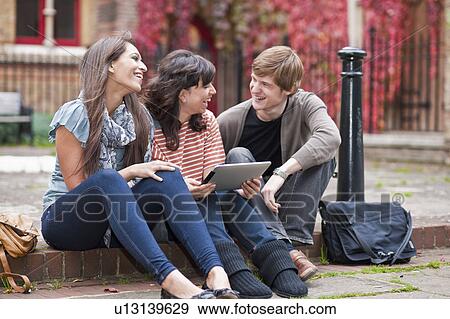 Friends sharing laptop outside View Large Photo Image Stock Photo - Friends sharing laptop outside. Fotosearch