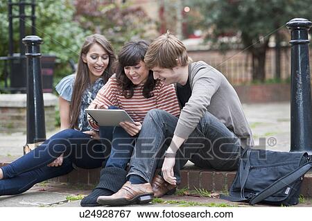 Friends sharing laptop outside View Large Photo Image Stock Photo - Friends sharing laptop outside. Fotosearch