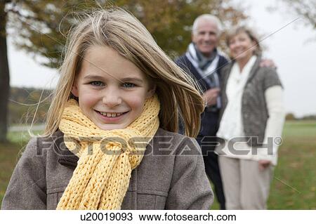 Stock Image - Girl and grandparents outdoors in autumn. Fotosearch
