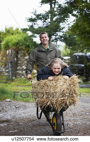 Picture - Girl being pushed in wheel barrow. Fotosearch