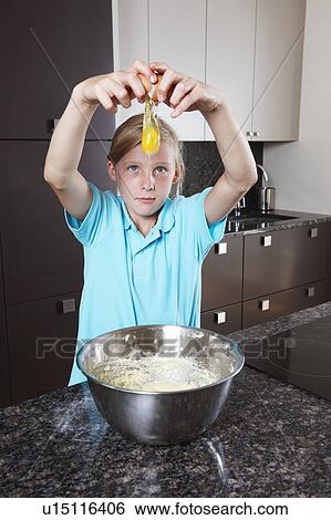 Stock Photograph - Girl breaking and egg over mixing bowl. Fotosearch