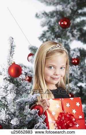 Girl by a chritmas tree, with a present View Large Photo Image Stock Image - Girl by a chritmas tree, with a present. Fotosearch