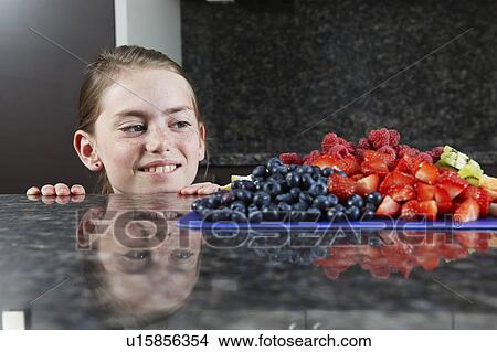 Picture - Girl choosing some fruit. Fotosearch