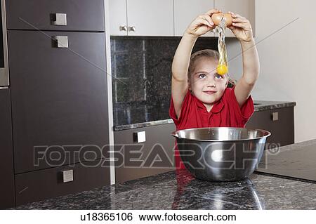 Stock Photograph - Girl cracking egg over bowl. Fotosearch