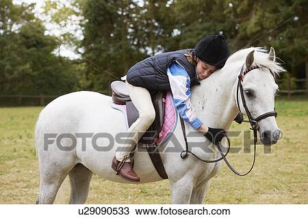 Stock Image - Girl cuddling her pony. Fotosearch