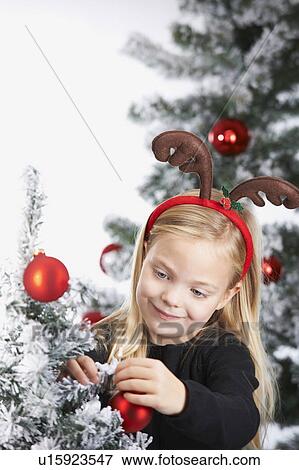 Stock Photo - Girl decorating a christmas tree. Fotosearch