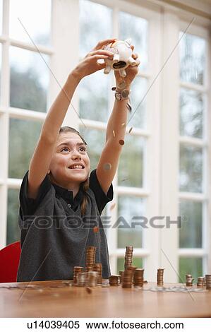 Stock Photography - Girl emptying her piggy bank of coins. Fotosearch