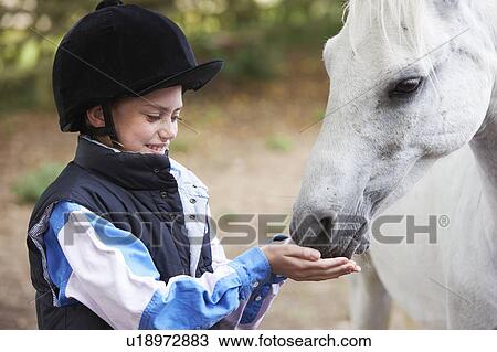 Stock Image - Girl feeding pony. Fotosearch