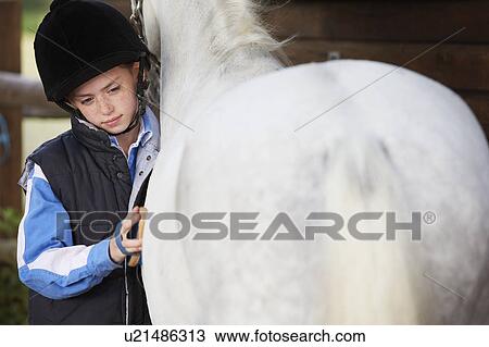Stock Image - Girl grooming her pony. Fotosearch