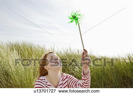 Girl holding up kids windmill in dunes View Large Photo Image Stock Photo - Girl holding up kids windmill in dunes. Fotosearch