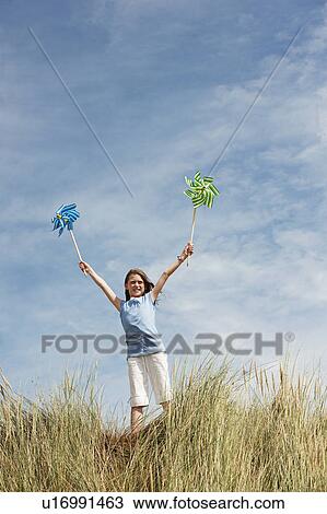 Girl Holding windmills in the sky View Large Photo Image Stock Image - Girl Holding windmills in the sky. Fotosearch