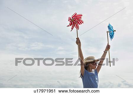 Girl holding windmills up in the sky View Large Photo Image Stock Image - Girl holding windmills up in the sky. Fotosearch