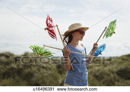 Stock Image - Girl in sand dunes with windmills. Fotosearch