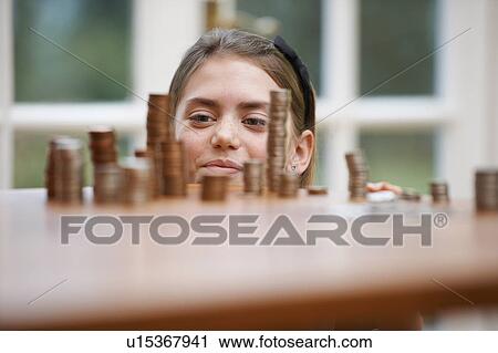 Girl looking at piles of money View Large Photo Image Stock Image - Girl looking at piles of money. Fotosearch