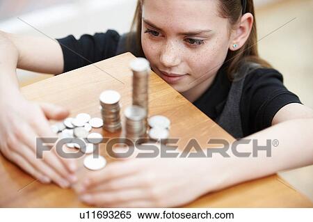 Stock Photography - Girl looking at piles of money. Fotosearch