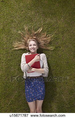 Girl lying holding a book View Large Photo Image Stock Photo - Girl lying holding a book. Fotosearch