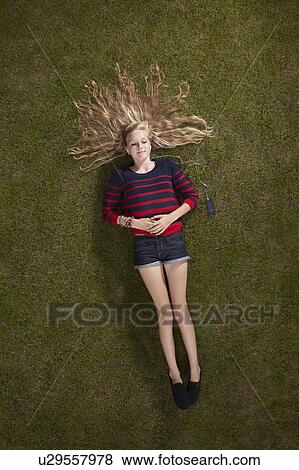 Girl lying listening to headphones View Large Photo Image Stock Photo - Girl lying listening to headphones. Fotosearch