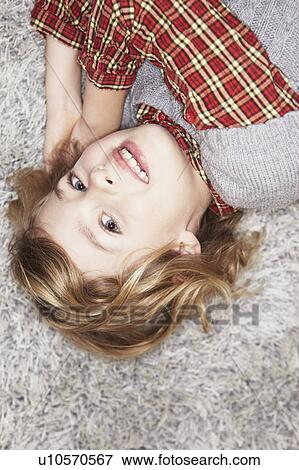 Stock Photo - Girl lying on carpet. Fotosearch