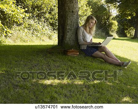 Girl on a computer under a tree View Large Photo Image Stock Image - Girl on a computer under a tree. Fotosearch