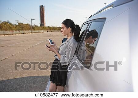 Girl on phone and PDA by car View Large Photo Image Stock Photo - Girl on phone and PDA by car. Fotosearch