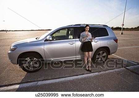 Stock Photography - Girl on phone by car. Fotosearch