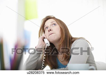 Stock Photography - Girl on the telephone sitting at desk. Fotosearch