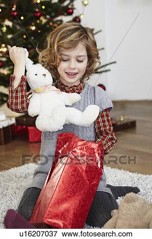 Stock Photo - Girl putting bunny out of present. Fotosearch