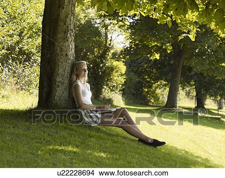 Girl relaxes under a tree View Large Photo Image Picture - Girl relaxes under a tree. Fotosearch