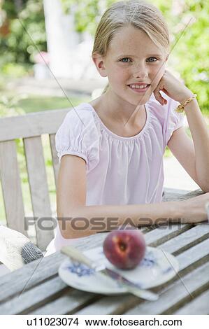 Girl sitting at table View Large Photo Image Picture - Girl sitting at table. Fotosearch