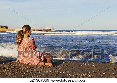 Girl sitting on the beach looking at sea View Large Photo Image Stock Photo - Girl sitting on the beach looking at sea. Fotosearch