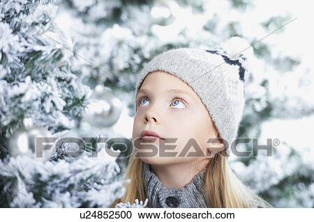 Stock Image - Girl standing between snowy trees. Fotosearch