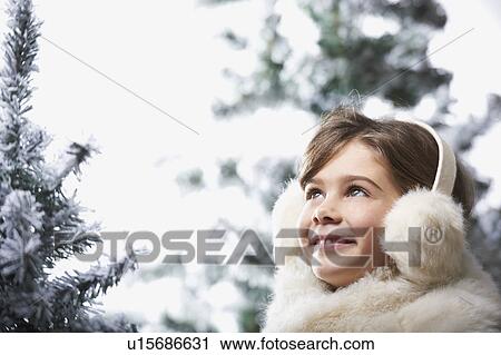 Stock Image - Girl standing by snowy trees. Fotosearch
