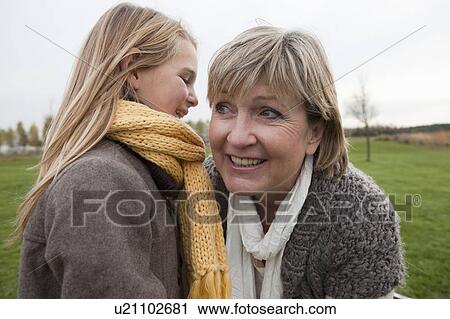 Girl whispering to grandmothers ear View Large Photo Image Stock Image - Girl whispering to grandmothers ear. Fotosearch