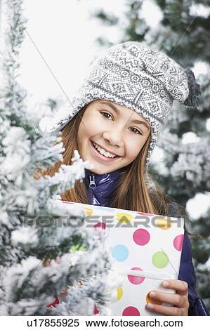Girl with a gift, next to snowy trees View Large Photo Image Stock Photography - Girl with a gift, next to snowy trees. Fotosearch