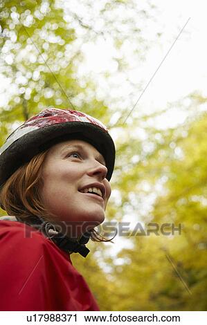 Girl with helmet looking up at trees View Large Photo Image Stock Image - Girl with helmet looking up at trees. Fotosearch