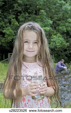 Stock Photograph - Girl with jam jar by the river. Fotosearch
