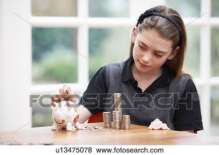 Girl with piggy bank and piles of money View Large Photo Image Stock Photo - Girl with piggy bank and piles of money. Fotosearch