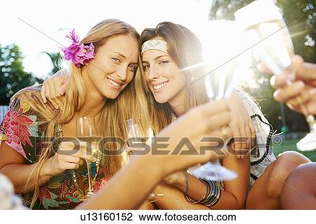 Stock Image - Girls celebrating with drinks by pool. Fotosearch