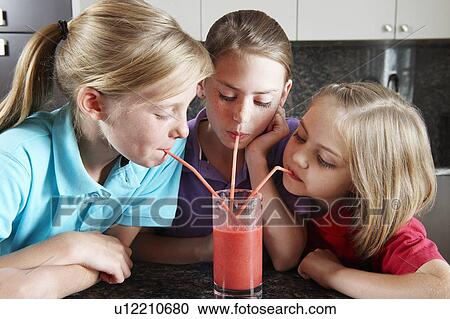 Stock Image - Girls drinking fruit juice with straws. Fotosearch