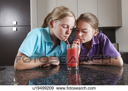 Girls drinking fruit juice with straws View Large Photo Image Stock Photo - Girls drinking fruit juice with straws. Fotosearch